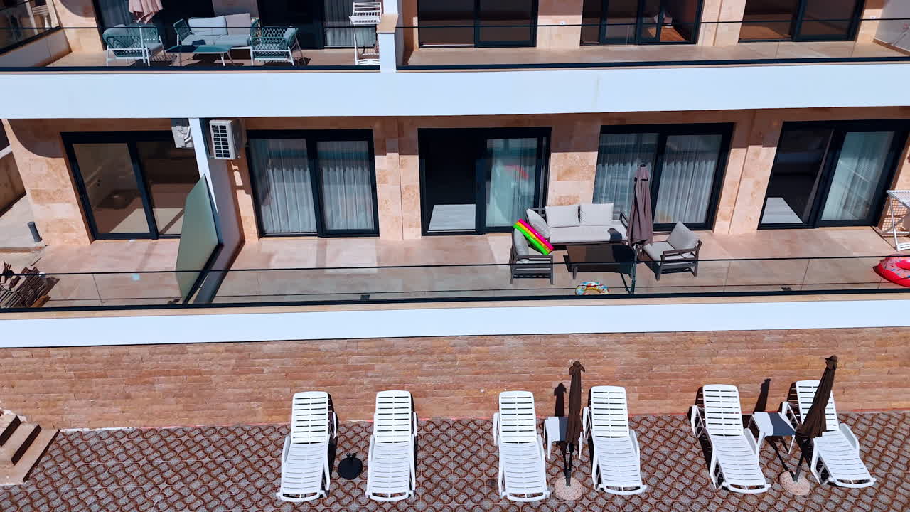 Flying closer to a hotel room with a swimming pool in front. Lush greenery surrounds the building. Montenegro. Aerial view