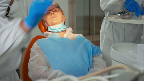 técnico de odontología en traje de abrigo lámpara de iluminación para examinar al paciente