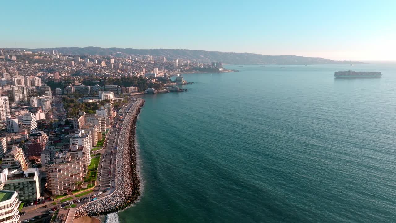 Dolly aereo in avvicinamento del lungomare Viale Perù vicino al mare turchese, edifici e montagne di Viña del Mar, Cile.