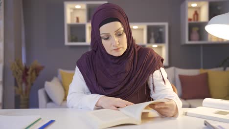 woman in hijab is reading a book at home.