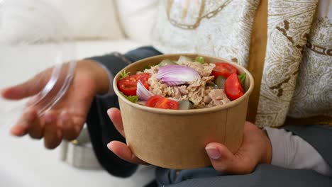 woman holding a tuna salad takeout container