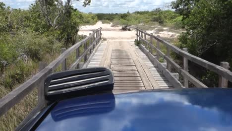 Off-road-Vehicle-Driving-Across-Wooden-Bridge-Towards-Dirt-Road