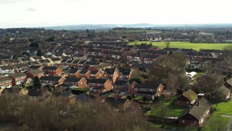 Rural-British-townhouse-neighbourhood-homes-with-green-space-aerial-descending-view-across-to-Snowdonia-mountain-skyline