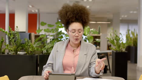 Retrato-De-Una-Mujer-De-Negocios-Birracial-Informal-En-Videollamada-En-La-Oficina,-Cámara-Lenta-Con-Espacio-Para-Copiar