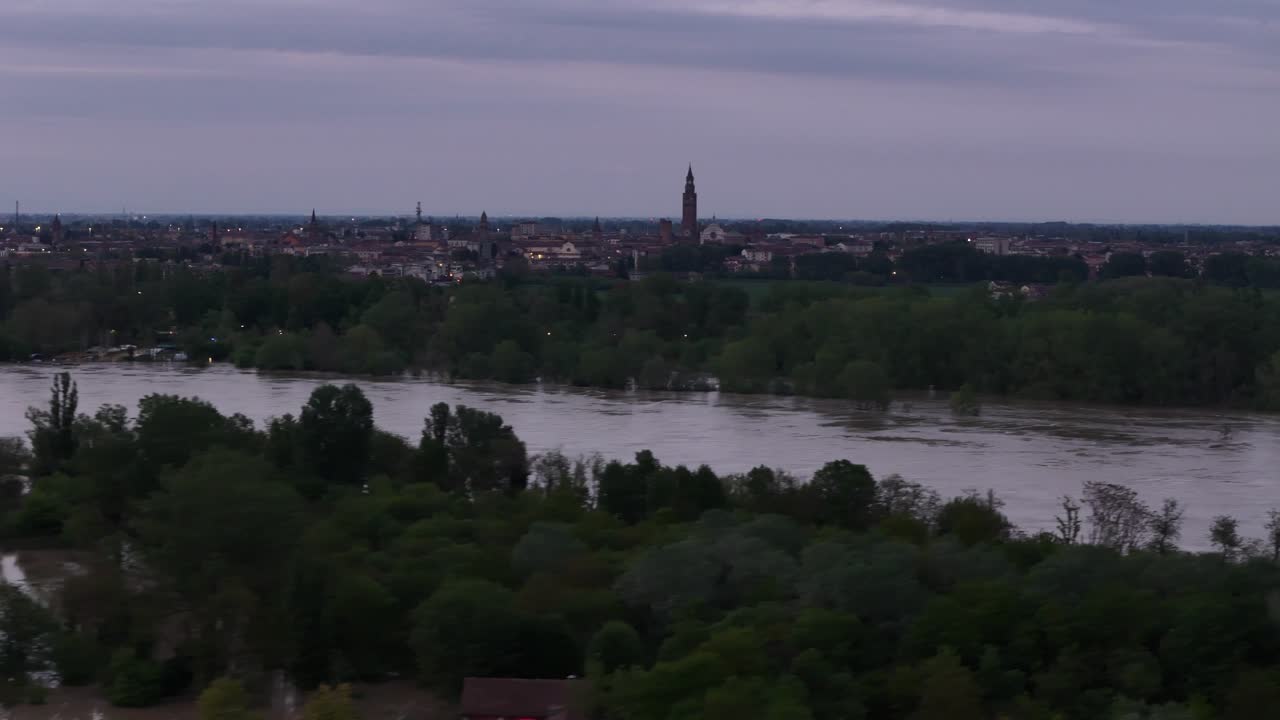 Dusk descends upon the flooded plains of Emilia Romagna, Italy, where the Po overflows its banks, submerging fields and houses, after heavy spring rainfall, with Cremona Lombardy accorss river