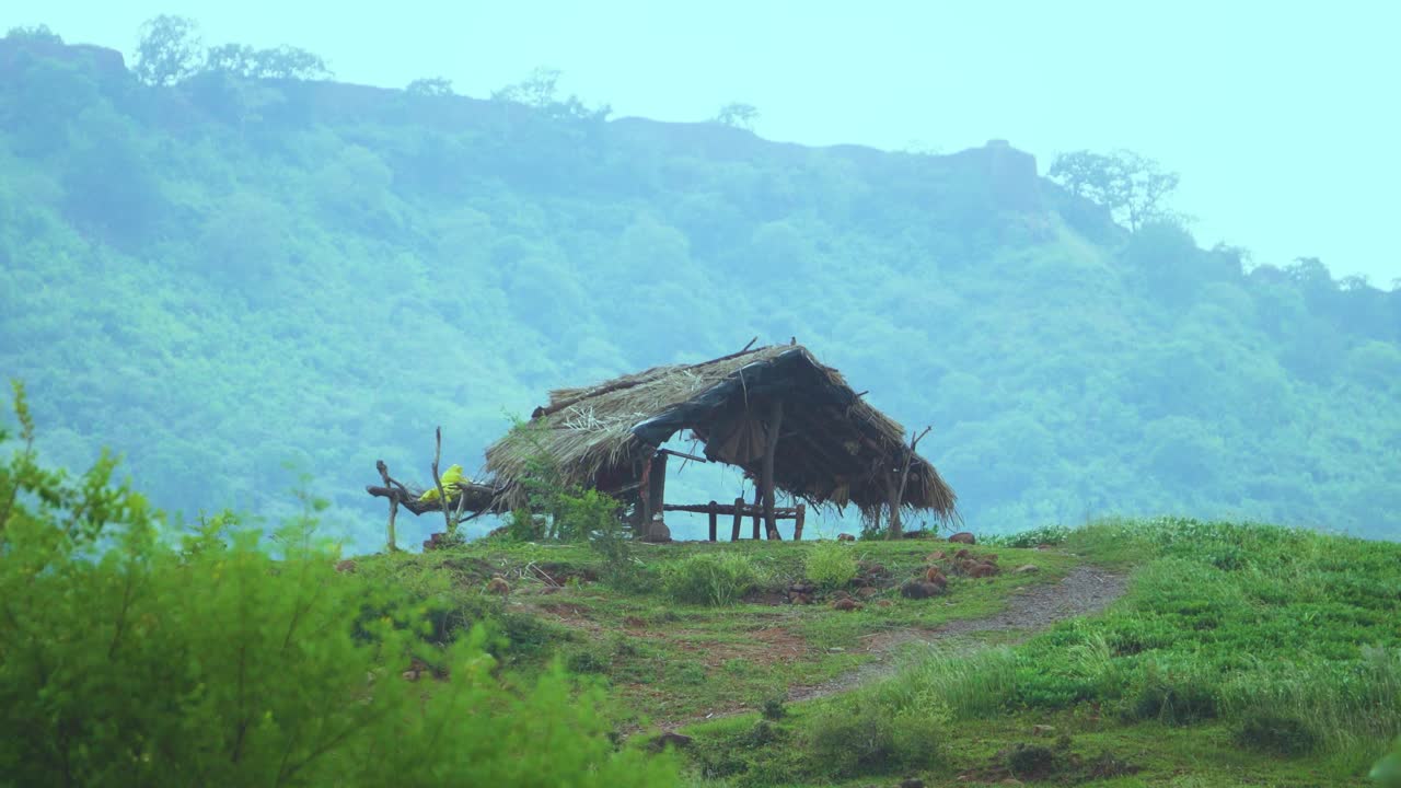 una cabaña de pueblo construida en la cima de una colina con fondo montañoso en un día lluvioso nublado en la india
