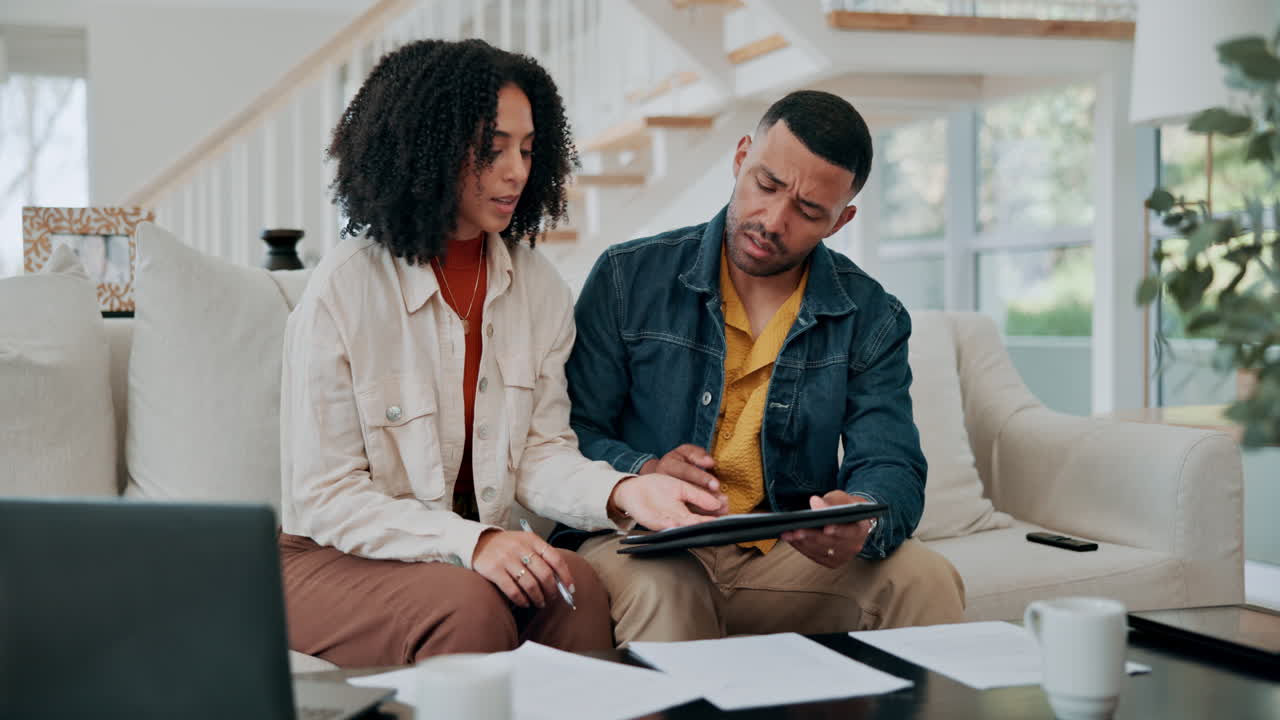 A couple is sitting at home reviewing paperwork and a laptop