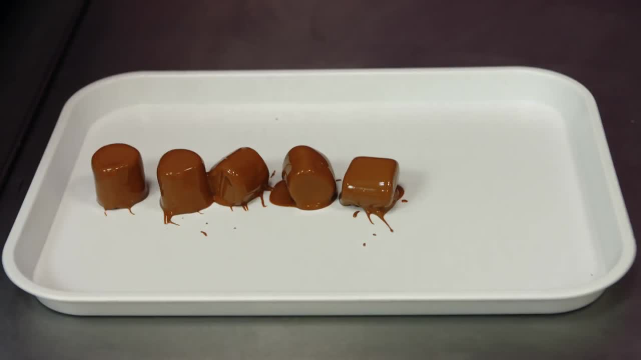 trabajador poniendo malvaviscos de chocolate sumergidos en la bandeja