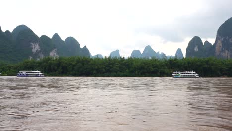 cruises on the li river with brown waters, surrounded by karst mountains