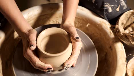 woman girl her hands dub wall jug, sculpts out of clay on circle.