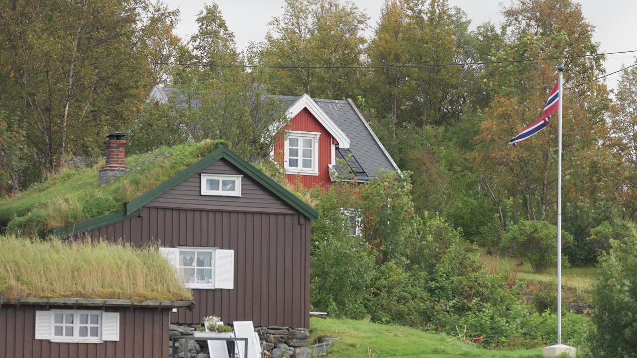 Hytter med torvtag og en moderne hytte i det norske landskab.
