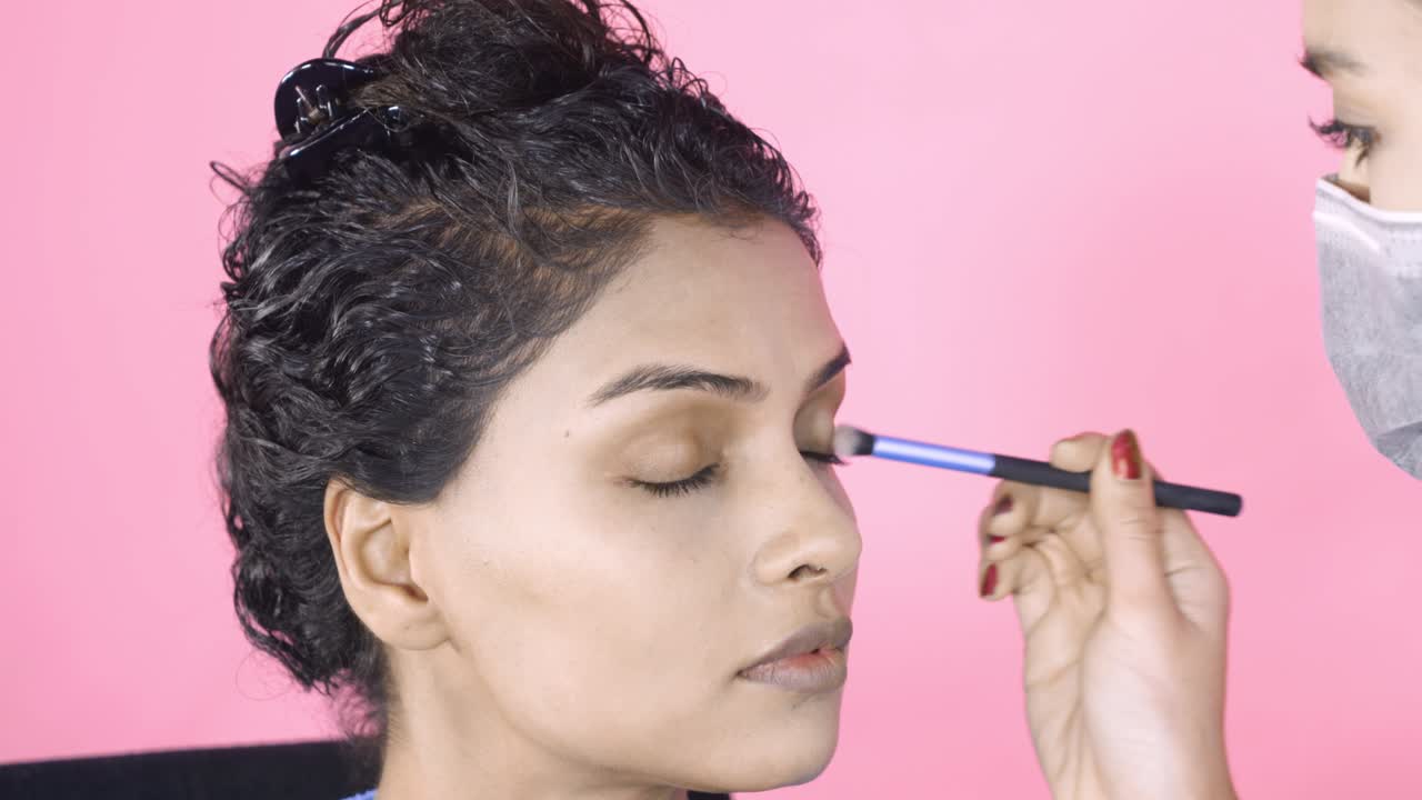 artista de maquillaje aplicando sombra para los ojos con un pincel