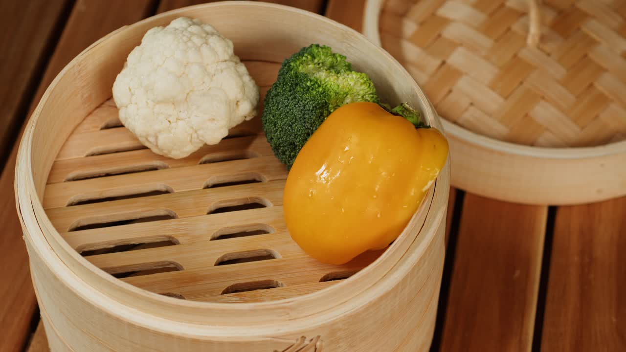 Steaming vegetables close-up. Wooden steamer for cooking.The concept of food and healthy eating. Yellow and green pepper, broccoli, carrot,cauliflower. High quality 4k footage