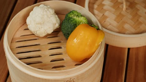 steaming vegetables close-up. wooden steamer for cooking.the concept of food and healthy eating. yellow and green pepper, broccoli, carrot,cauliflower. high quality 4k footage