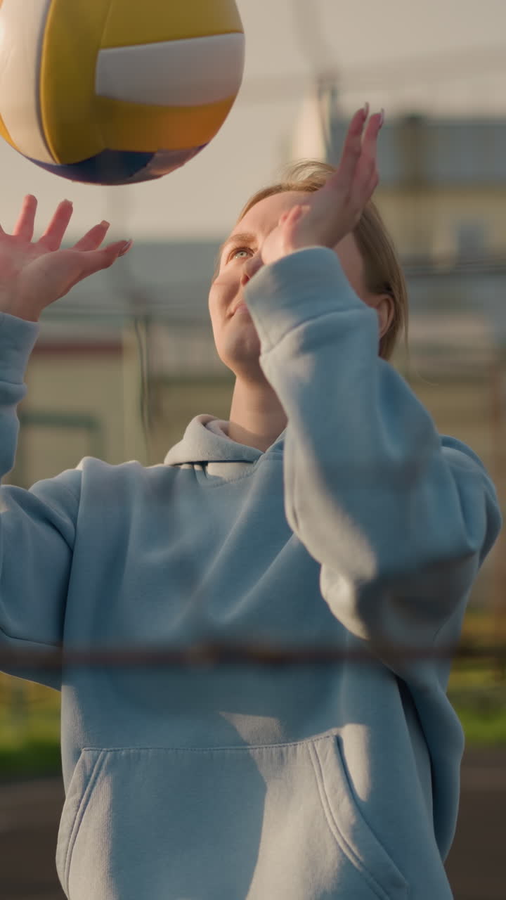 primer plano de la red de voleibol en acción con el jugador visible en el fondo preparándose para una jugada, fondo borroso con vegetación y un edificio