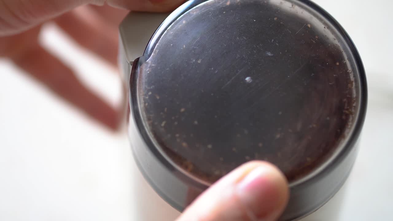 백인 남성 손은 투명한 뚜껑이 있는 볶은 황금빛 갈색 콩으로 가득 찬 오래된 커피 그라인더를 닫고 미세한 가루로 분해합니다.