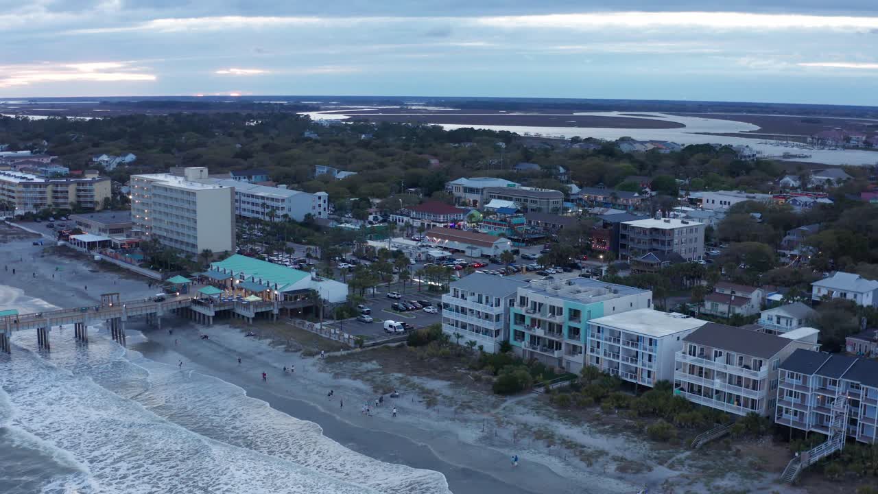 una fotografía aérea de cerca de la playa de folly en la isla de folly, en carolina del sur, al atardecer.