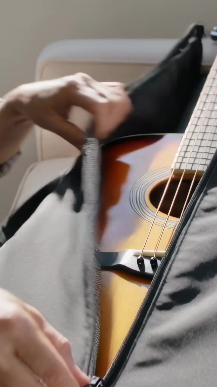 Vertical video: Grasping zipper aged hands unzipping black case at home revealing guitar to play