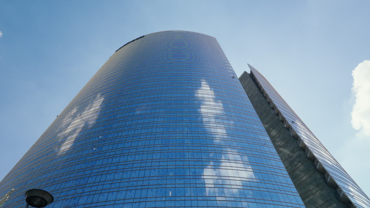 rascacielos moderno en milán con fachada de vidrio reflectante y cielo azul