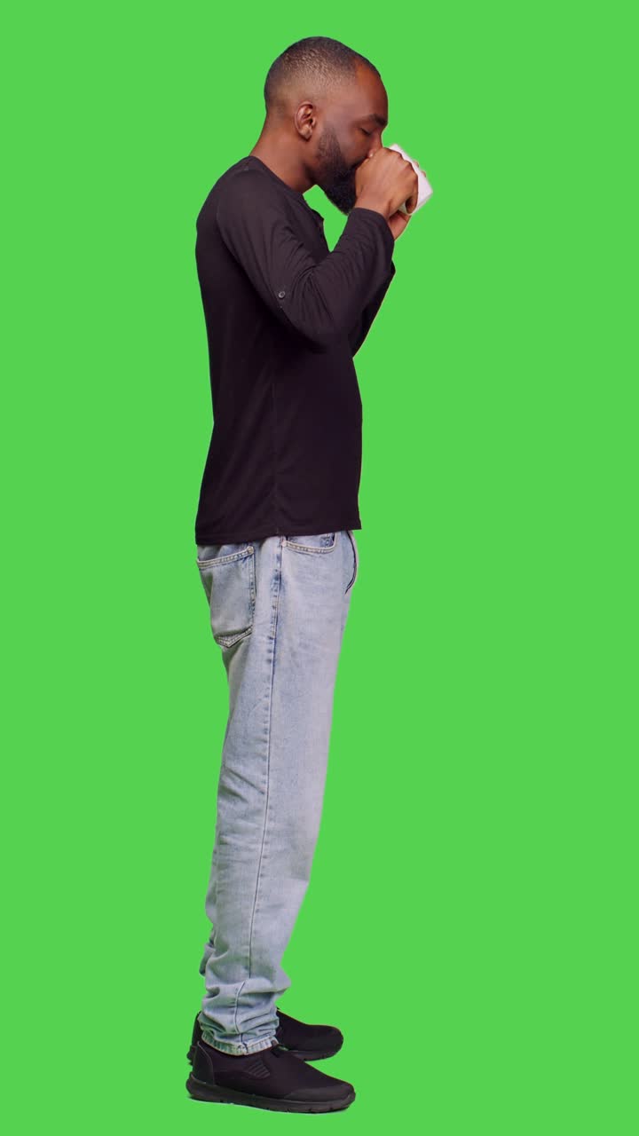 Video verticale: profilo di giovane che beve caffè su greenscreen a figura intera