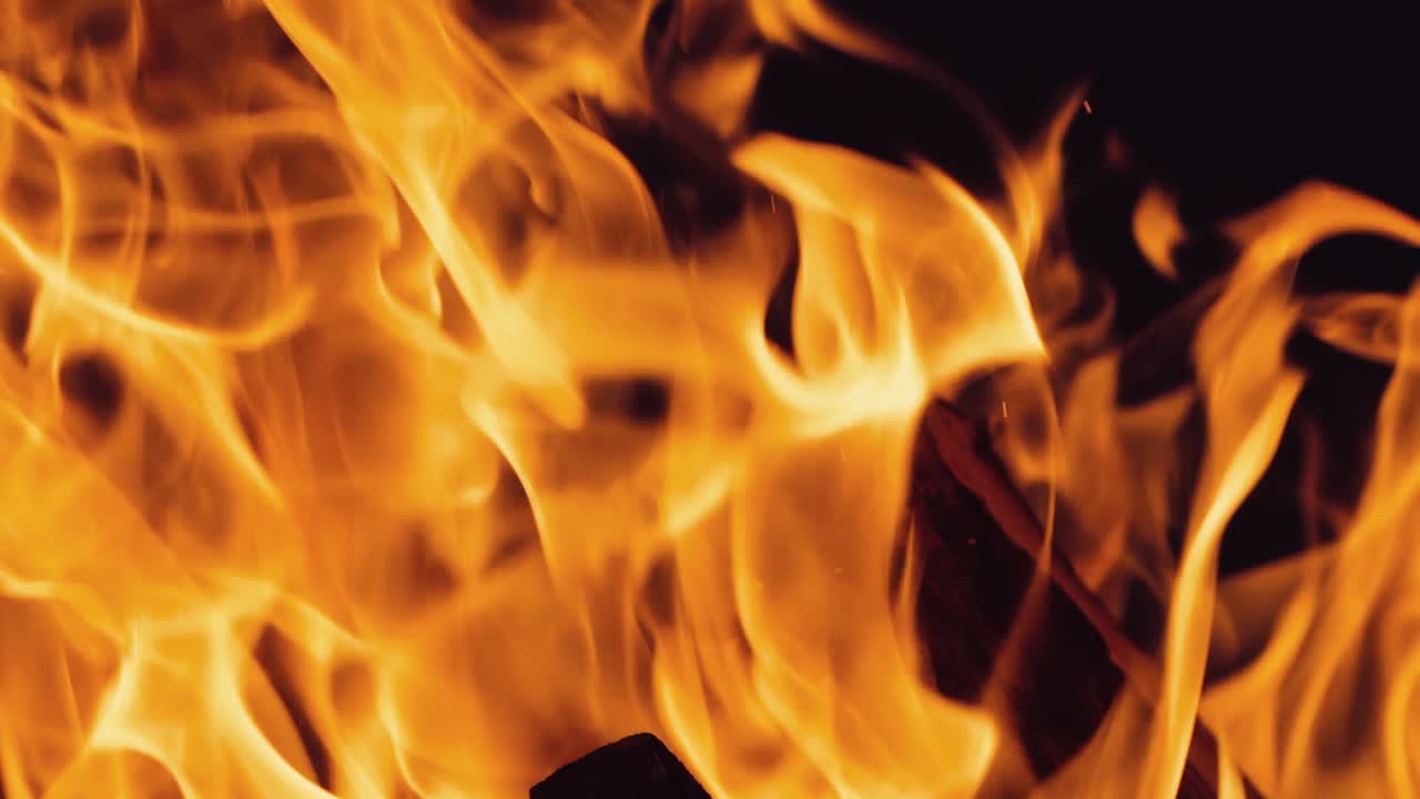 Falò che brucia di notte. Fiamme di fuoco su sfondo nero al rallentatore.