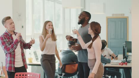 Equipo-Alegre-Celebrando-El-éxito-En-El-Lugar-De-Trabajo.-Amigos-Felices-Bebiendo-Alcohol.