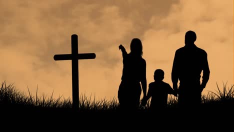 animation of silhouette of christian cross and family with one child over orange clouds