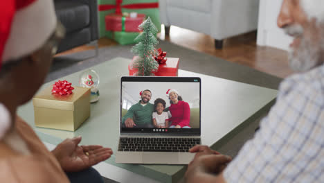 Happy-african-american-senior-couple-on-laptop-video-call-with-family-at-christmas-time