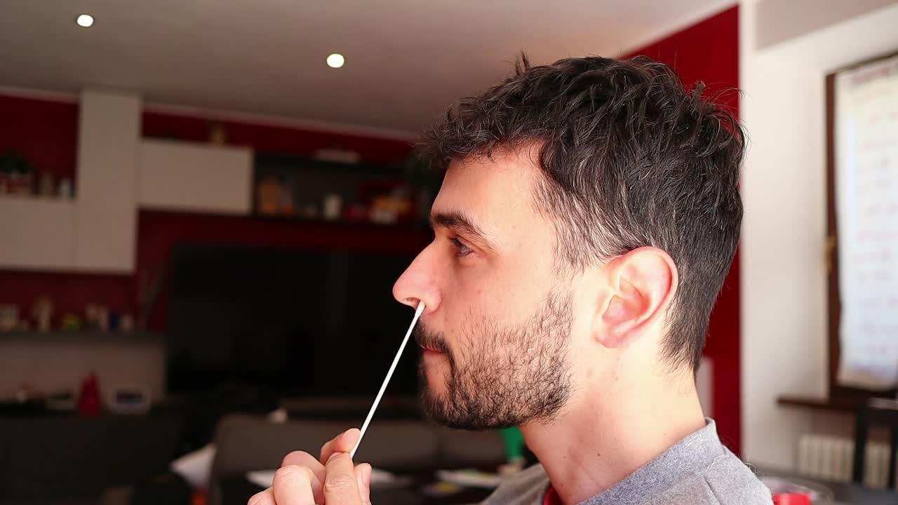 백인 남성이 스스로 코로나 면봉을 만들고, 측면 샷을 닫습니다.