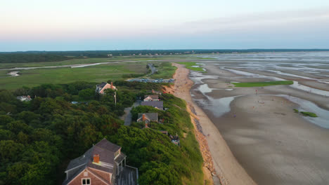 cape cod bay aerial drone footage of bay side beach at low tide with sand dunes, marsh and people walking in ocean during golden hour