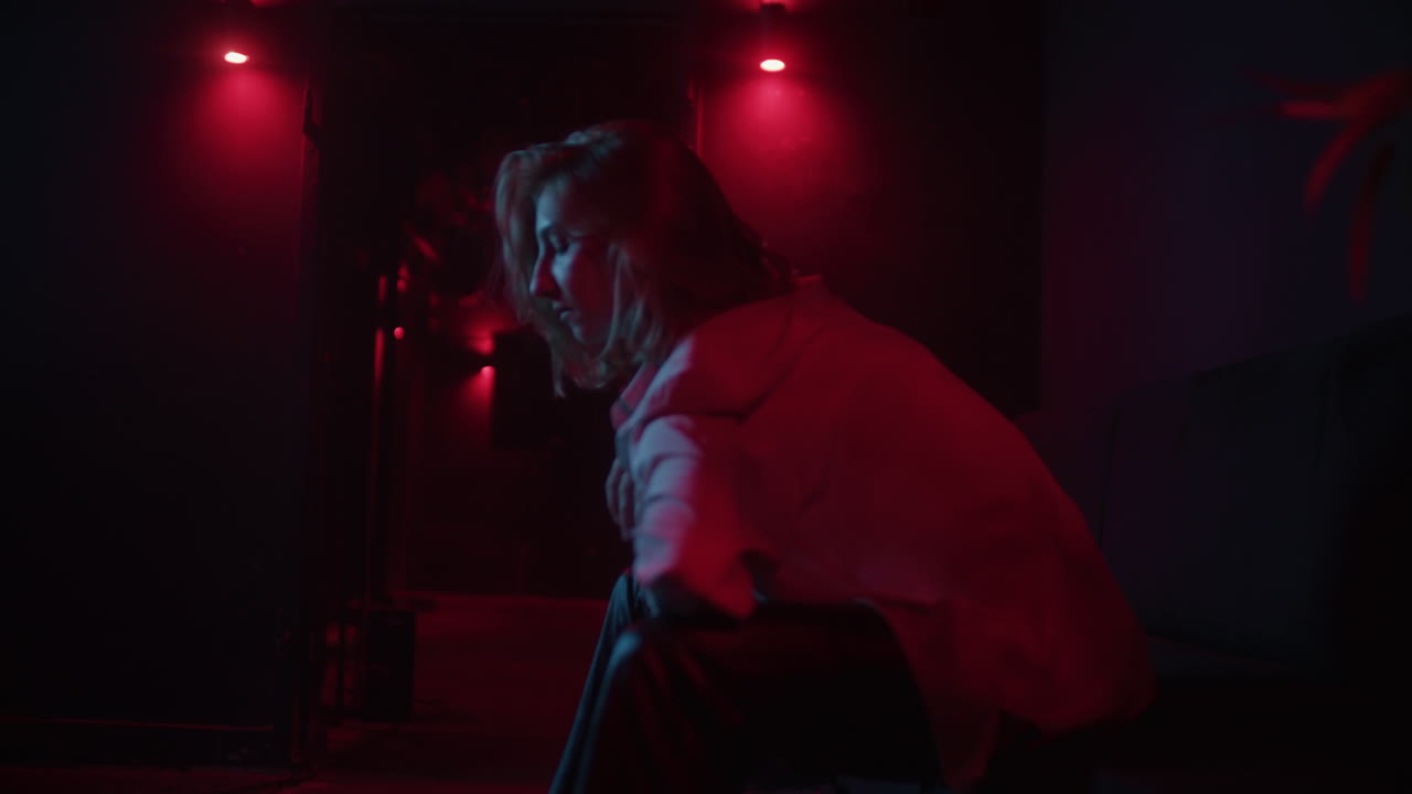 Woman Sitting in a Dark Room with Red Lights