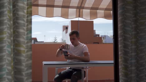 happy man texting on a smart phone outdoors sitting in the balcony during a sunny day