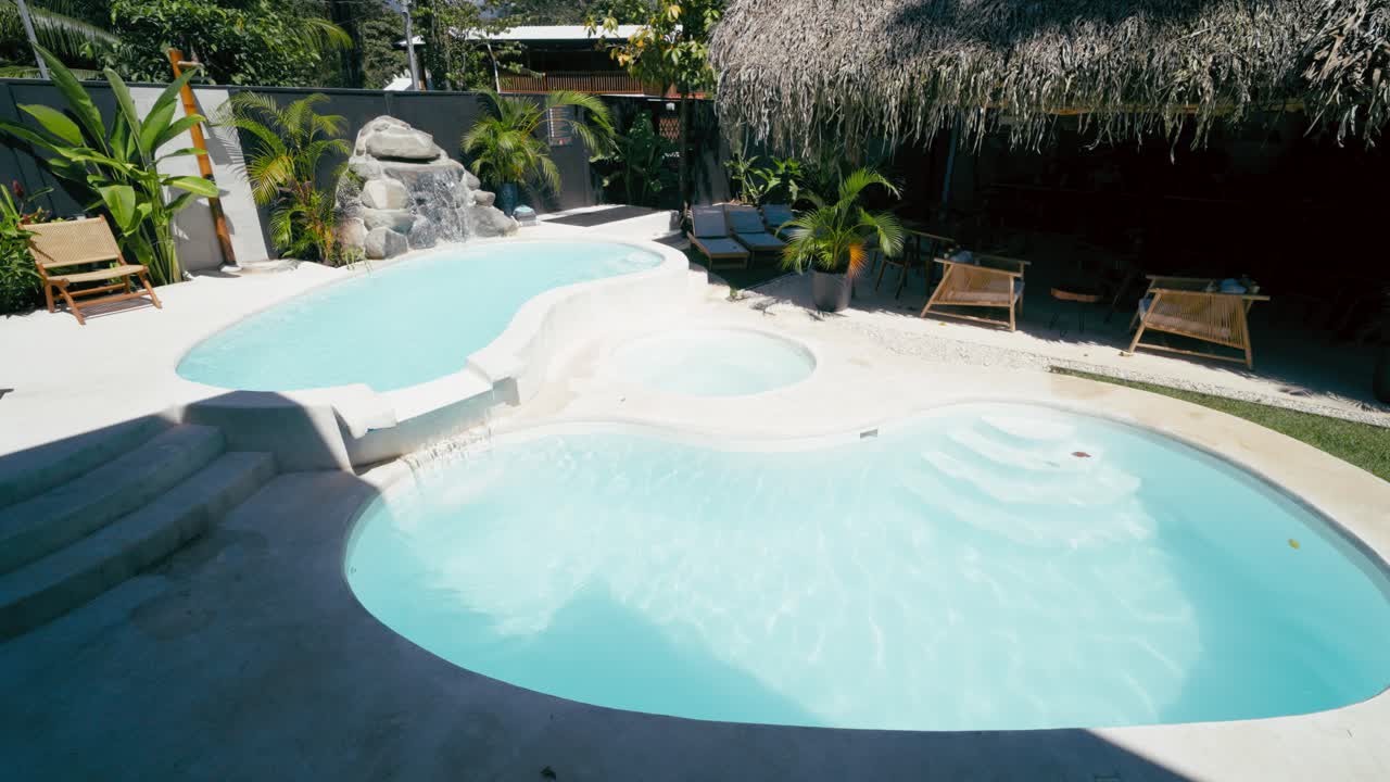 Smuk tropisk resort swimmingpool med vandfald og spabad.