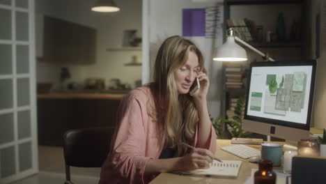 female designer having phone talk in evening at home