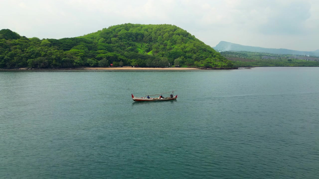 Scena marina idilliaca: una barca da pesca locale passa vicino alla spiaggia di Tampora, Giava Settentrionale, Indonesia 4K 60FPS