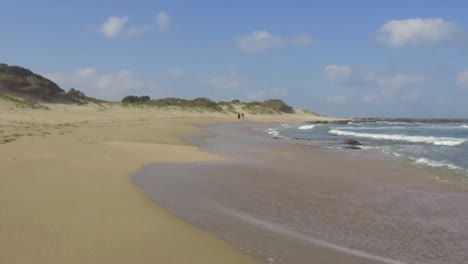 a couple walking along the shore line at glen gariff beach