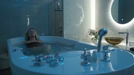 satisfied young woman with closed eyes relaxing during hydromassage treatment in spa salon. pleasure from hydromassage procedures
