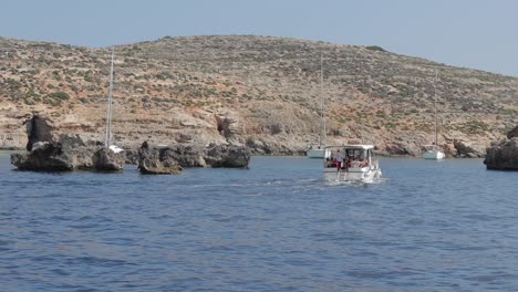 una pintoresca vista de la costa de malta, con barcos atracados cerca de la costa y islas con escasa vegetación bajo un cielo soleado, mostrando belleza natural y tranquilidad