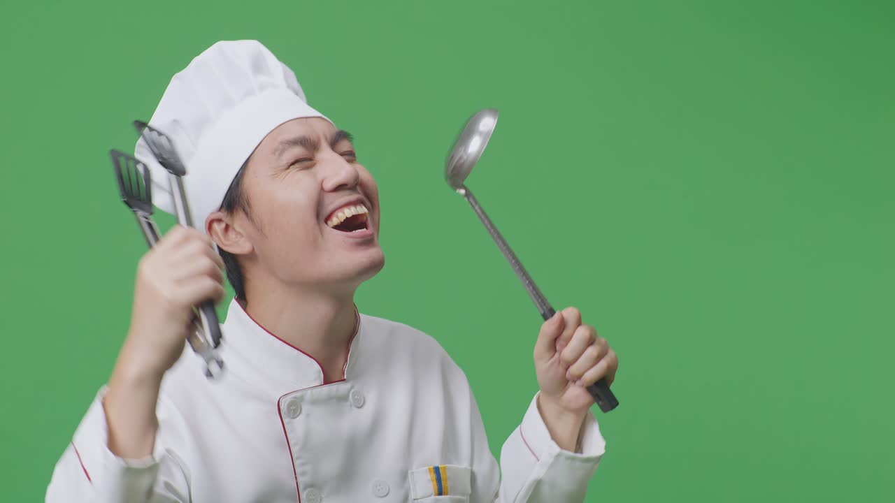Close Up Of Asian Man Chef Holding Tongs And Ladle And Dancing While Standing In The Green Screen Background Studio