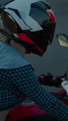 a lady rides a red power bike along a tarred road, her shirt billowing in the wind and exposing part of her body as she leans forward, gripping the handlebar