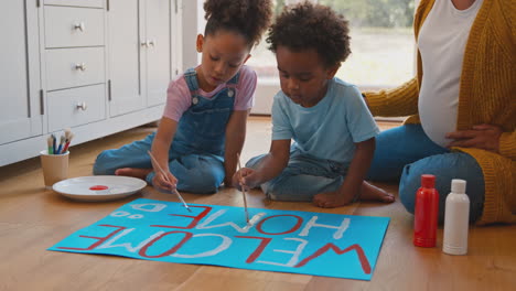 pregnant mother with children making welcome home banner for army father