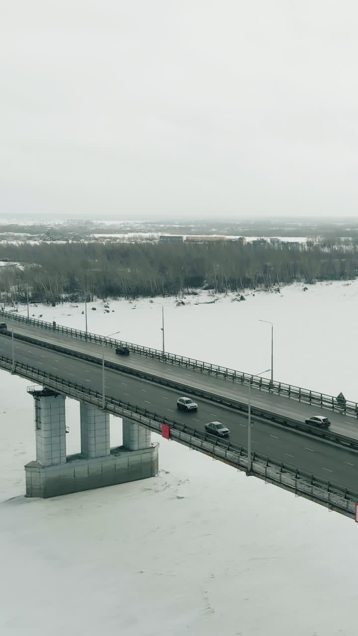 highway for fast moving vehicle located on high wide bridge running over frozen river against forest aerial view