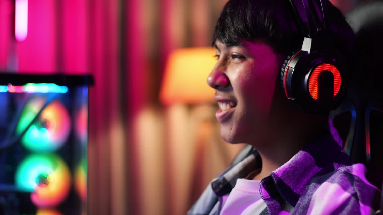 흥분한 아시아 십대 소년 게이머가 승리를 축하하고 컴퓨터에서 비디오 게임을 하는 동안 춤을 추고 있습니다.