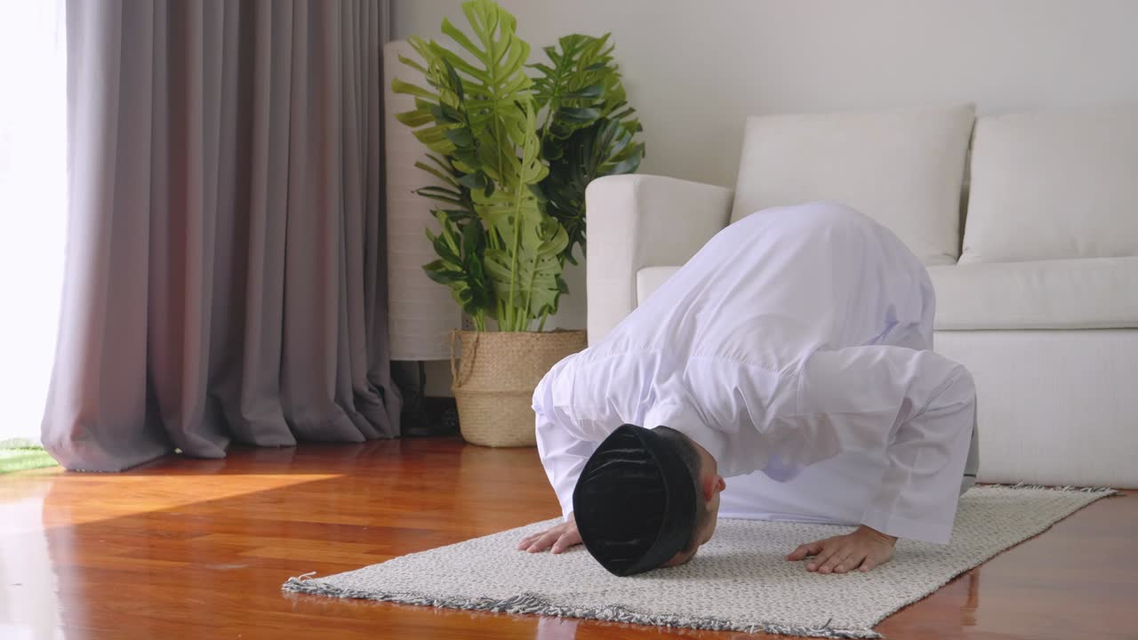 아시아 젊은이 무슬림은 거실에서 축복을 받기 위해 기도합니다. 이슬람에 대한 믿음 무슬림들은 매일 집에서 자신과 가족에게 축복을 주기 위해 기도를합니다.