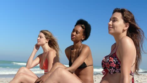 young female friends sitting together at beach 4k