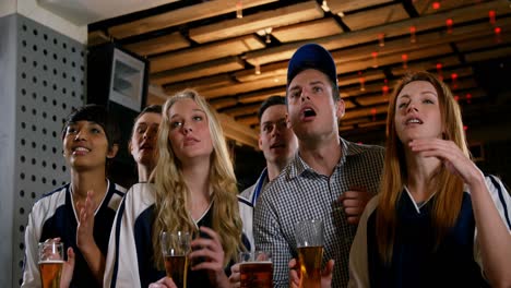 group of friends watching tv in bar