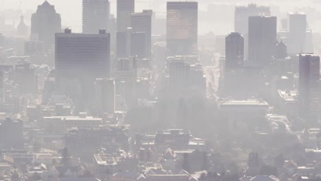 general view of cityscape with multiple modern buildings covered in smog