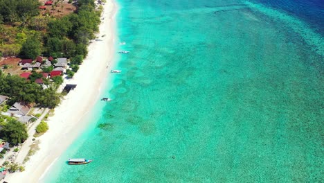 Beautiful-beach-coastline-with-shallow-aqua-waters-and-small-boats-docked-at-the-shore