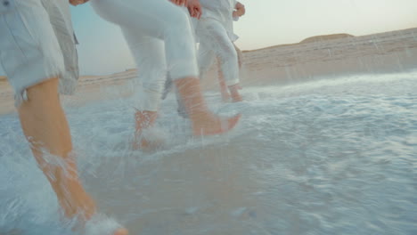 four people splashing sea water with feet