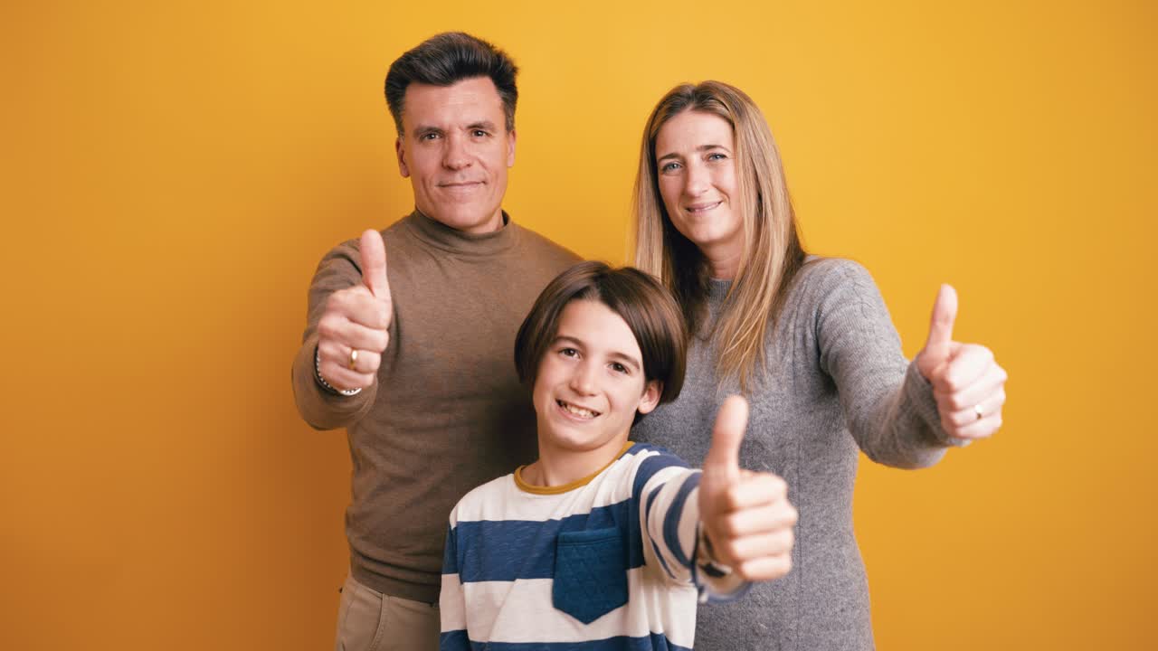 Happy Family Giving Thumbs Up Gesture on Yellow Background